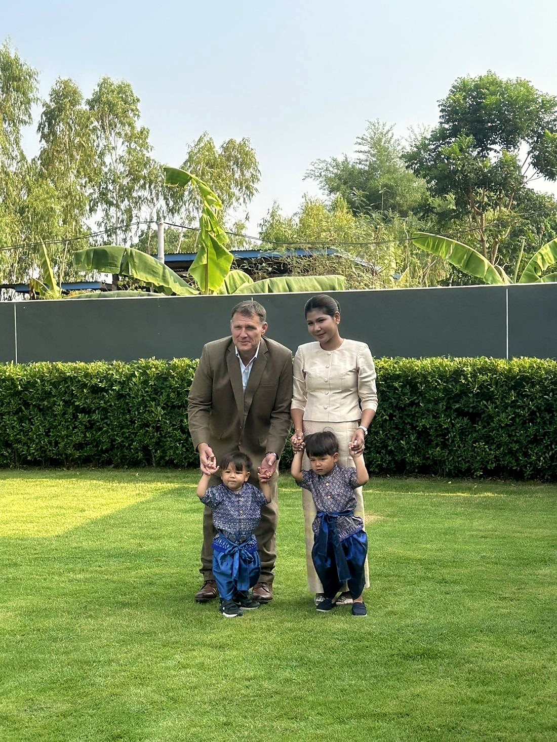 Ben, Ploy and their sons in Thai dress on the lawn