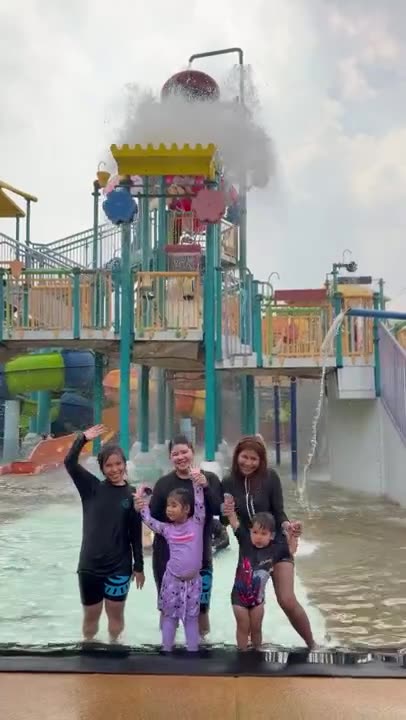 Ploy and the children under the tipping bucket at a water park